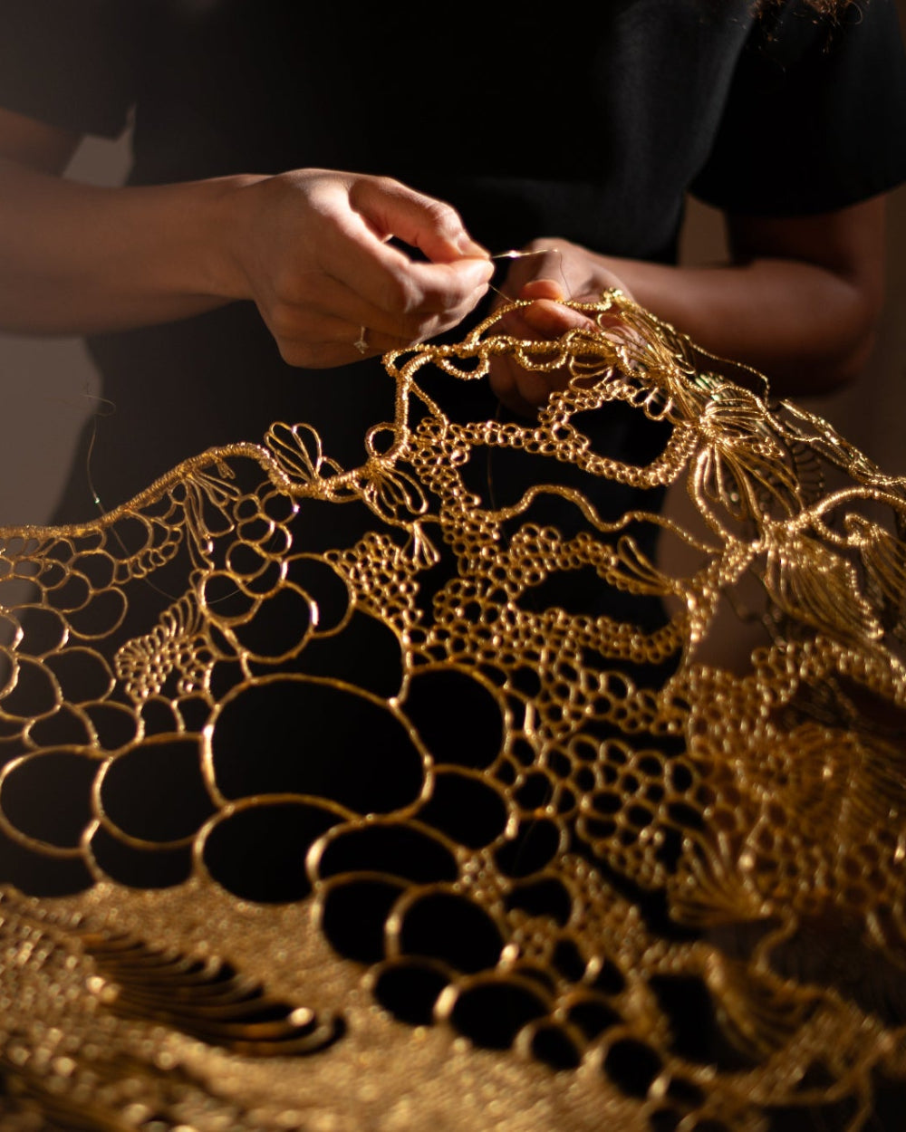 Marie De Decker’s hands shaping a gold filigree sculpture